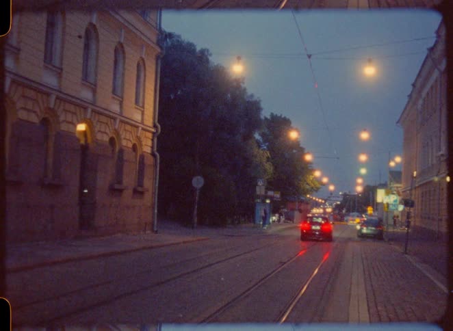 Car driving down the streets of an urban area outdoors with other cars driving around and pedestrians walking on the sidewalk