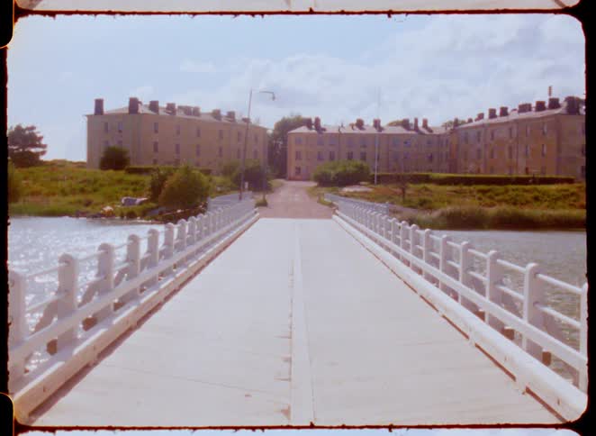 White bridge leads to old buildings surrounded by green areas
