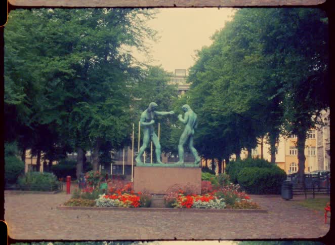A statue of two people fighting are in the park