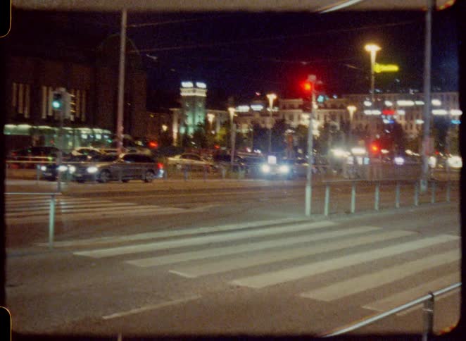A group of people crossing a zebra crossing in the city at night while other motorists remain stopped