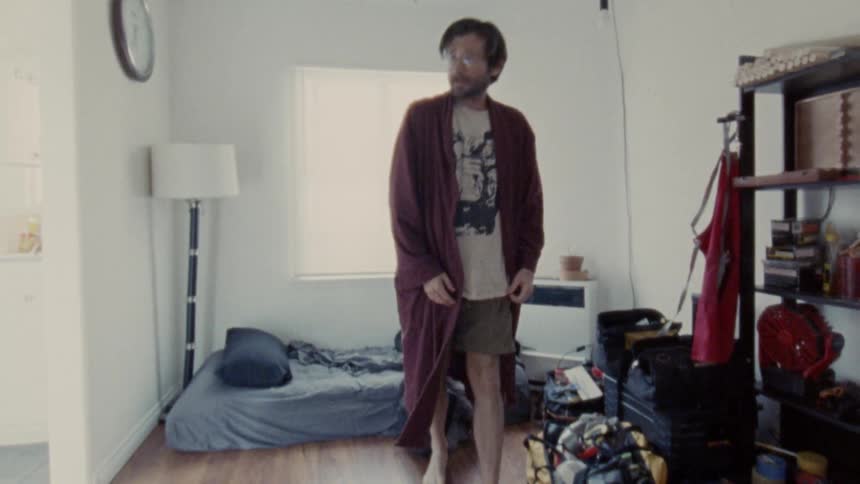 The man gets up and walks through his home