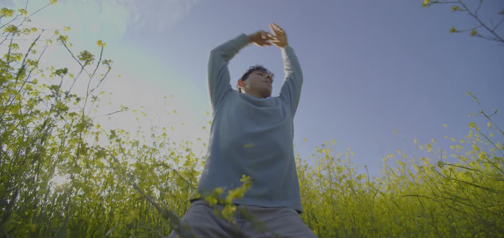 The man is practicing tai chi in the tall flowers