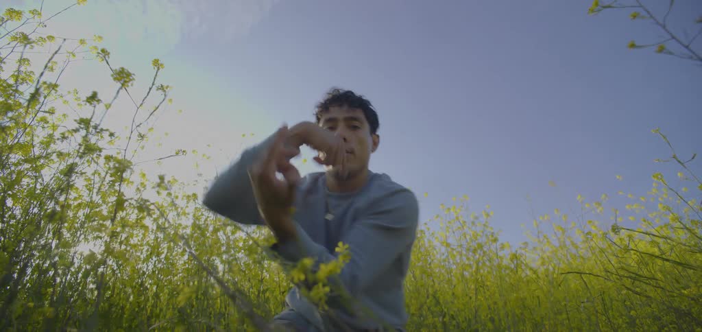 A man with a joyful expression dancing in a field of yellow flowers surrounded by the blooming plants