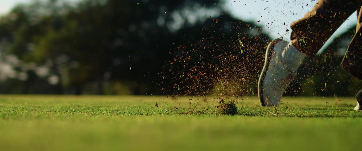 The man picks up dirt when hitting the golf ball