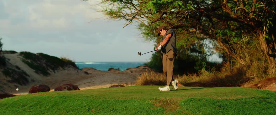 The man is playing golf and driving the ball