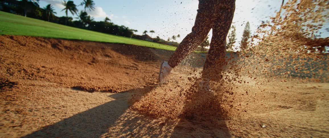 Person throwing a golf ball into the sand