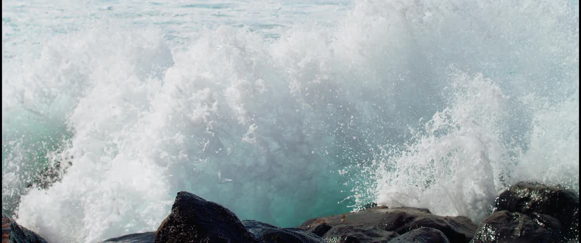 Waves splash as they roll into shore and crash against the rocks along the coast