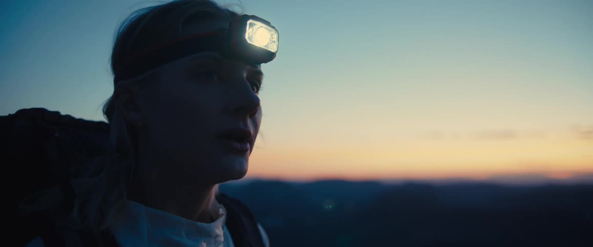 Woman with a flashlight on her head on a mountain in the late afternoon