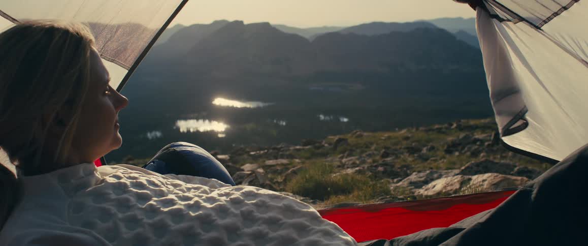 The woman lays in her tent on the mountain