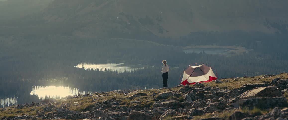 Woman coming out of a tent on a mountain