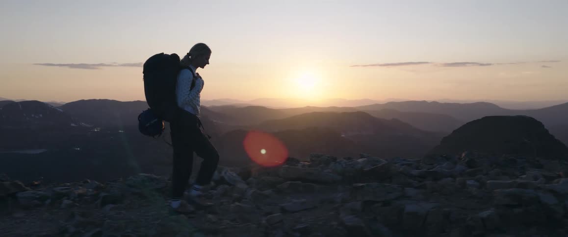 Person hiking with a large backpack at sunset in the mountains