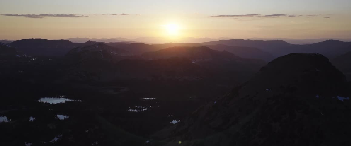 Sun at the horizon next to a mountain range outdoors during dusk or dawn