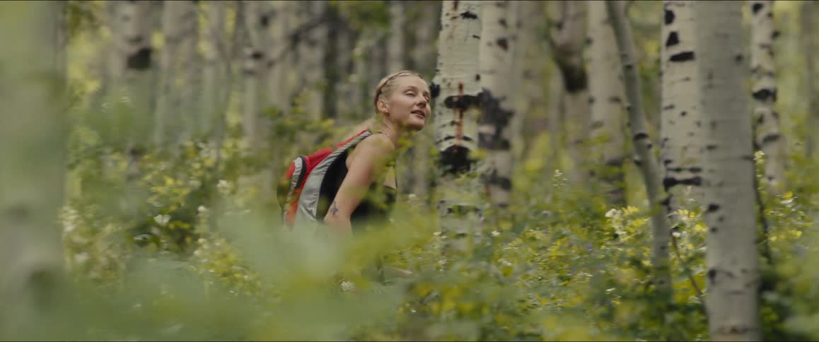 Blonde female hiker walks through the woods