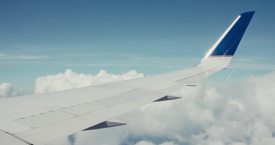 Wing of an airplane flying over the clouds outdoors during day time