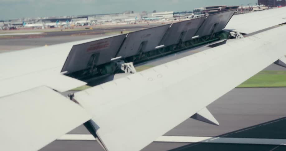 Wing of an airplane landing on the runway of an airport outdoors during day time