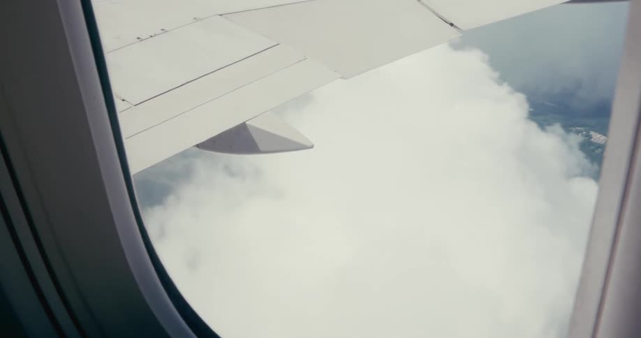 View of the planes wing between the clouds seen from the window