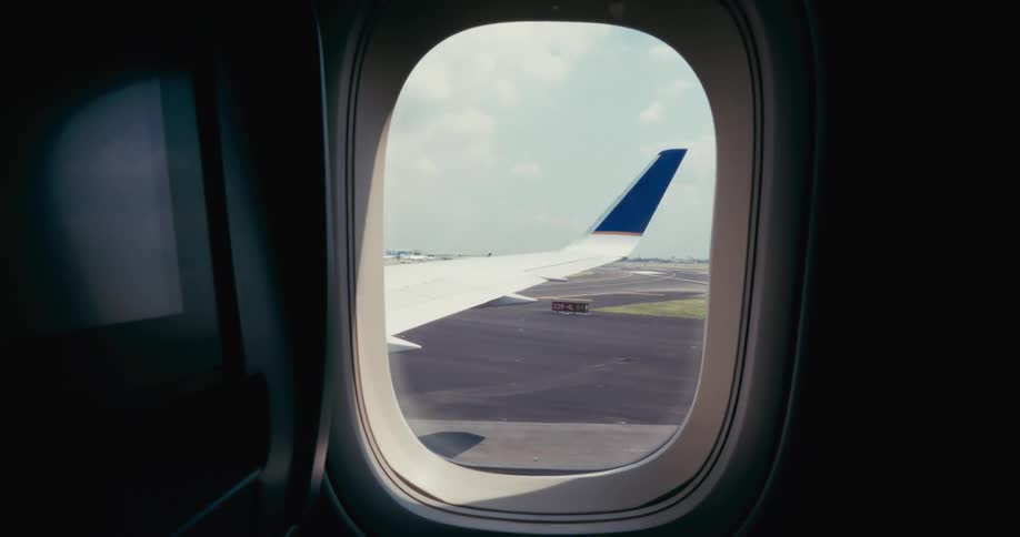 An airplane wing through the window as the flight moves down the runway