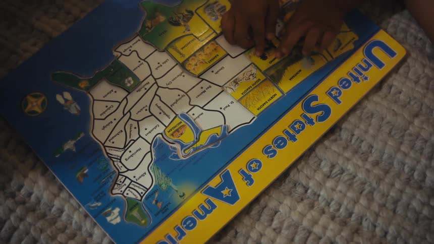 Hands of toddlers playing with a puzzle indoors