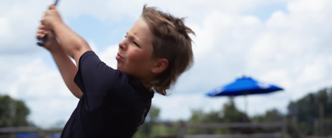 The child swings the golf club on a cloudy day