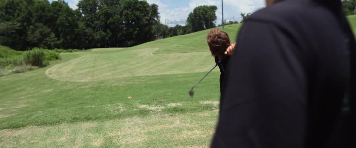 The child hits the golf ball during a game
