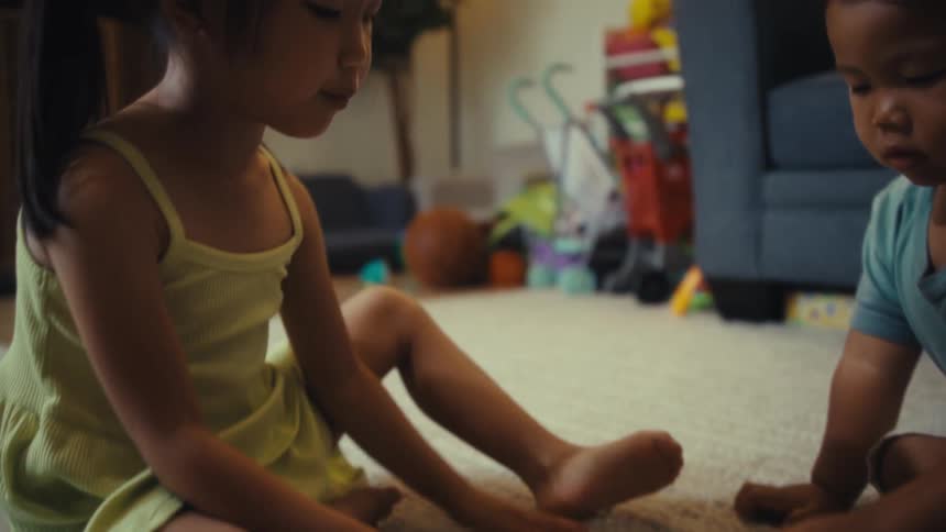 Two children sit on the floor playing with puzzle pieces