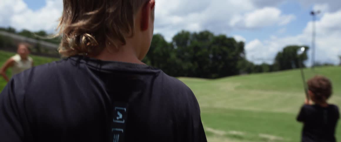 Two people watching a child play golf on a course