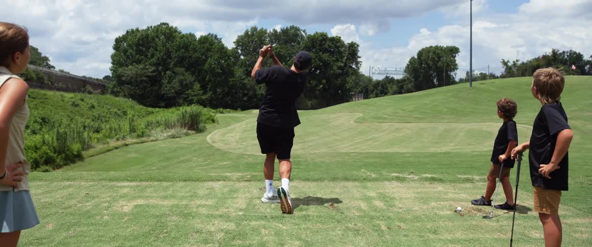 The children watch the man drive the golf ball