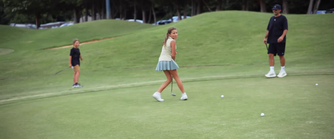 Family gathered on a grassy course casually playing golf