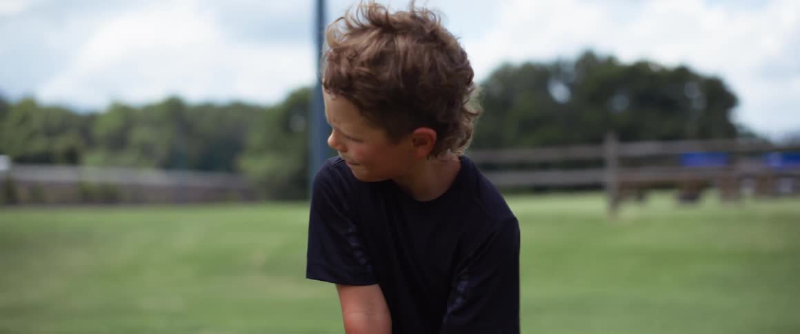 A young boy swings a golf club and hits a ball outdoors