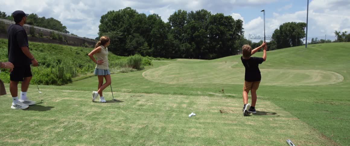A family plays golf together on a grassy course