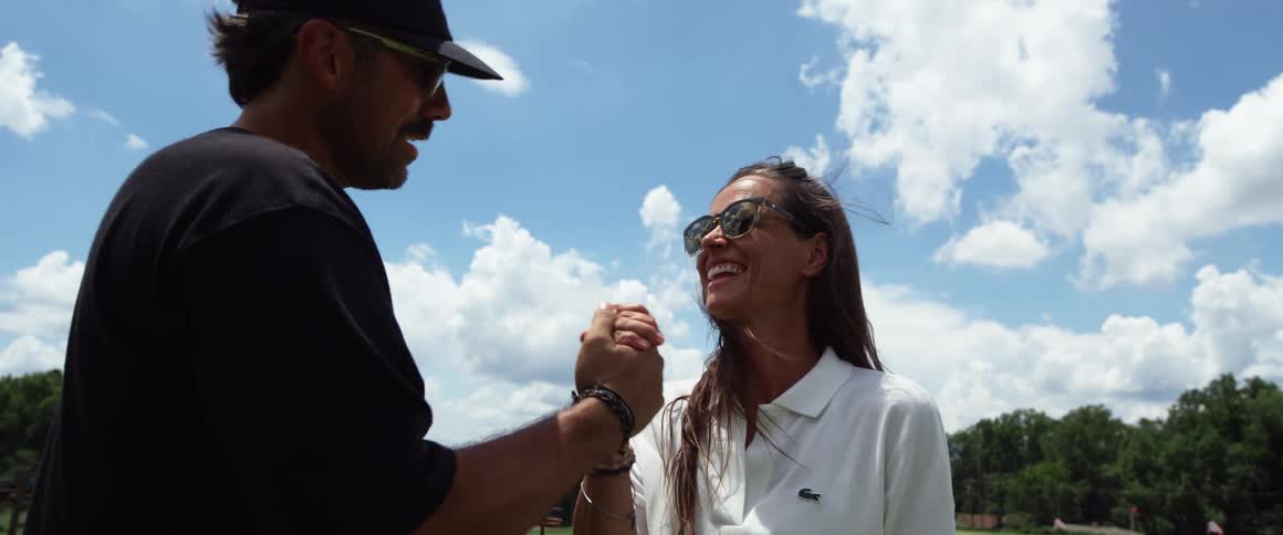 A man and woman shake hands on the golf course
