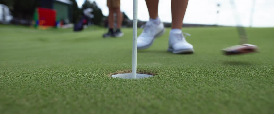 The woman hits the golf ball in the hole