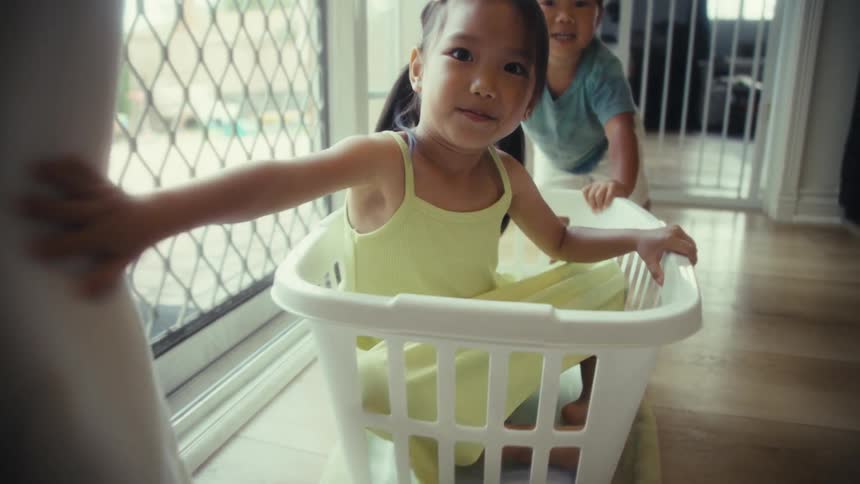 A girl is pushed in a basket through the hallway