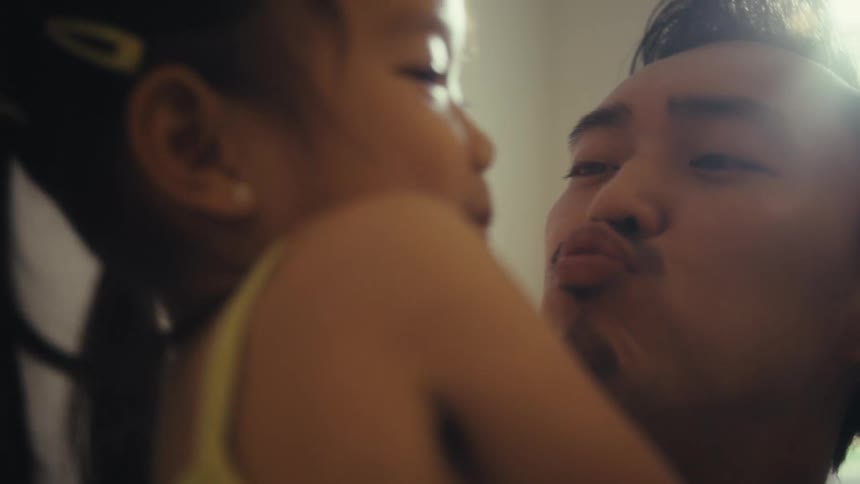 Closeup of a father playfully kissing his daughter