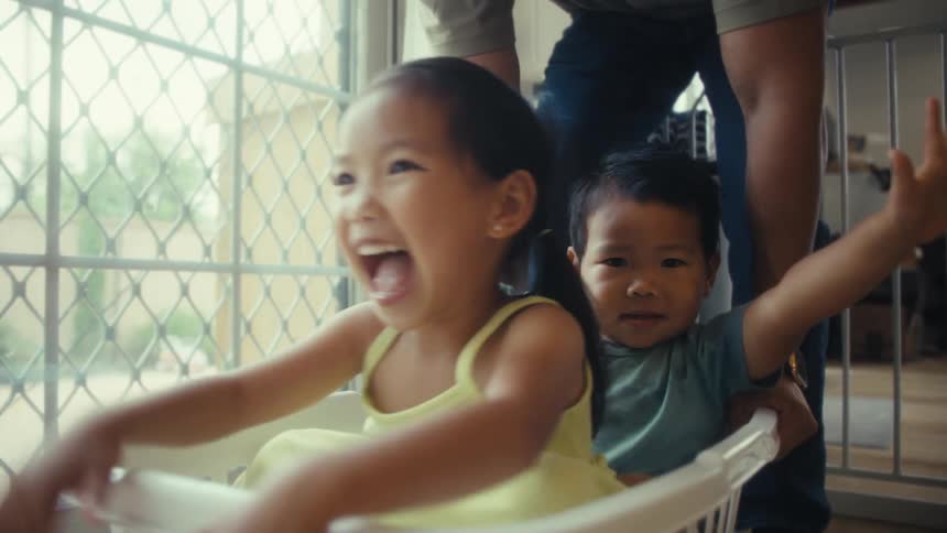 Children play joyfully inside a basket pushed by their father