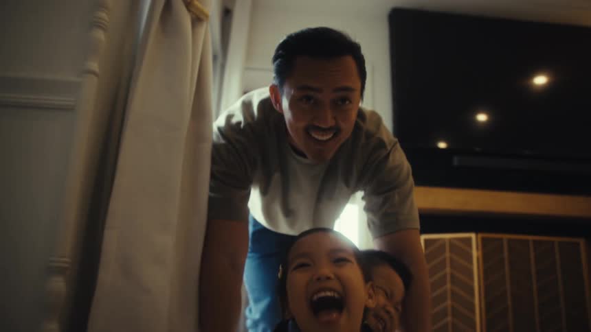 The man is pushing a basket with his children laughing in it