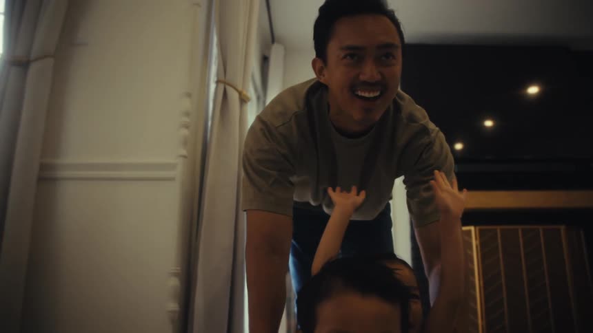 An adult pulls a laundry basket with his son and daughter sitting inside it across a floor