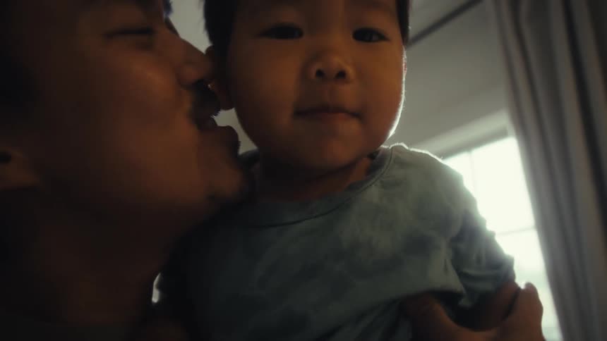 A father having fun with his infant son carrying him in the living room at midday