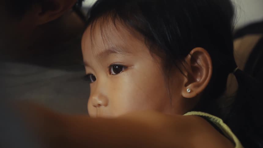 Closeup of a young child seated next to a man on a couch indoors