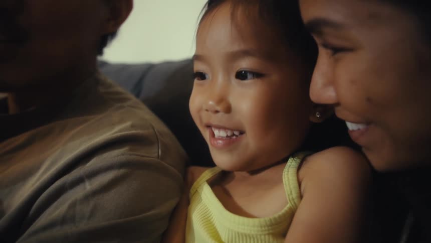 A family sit together on the couch