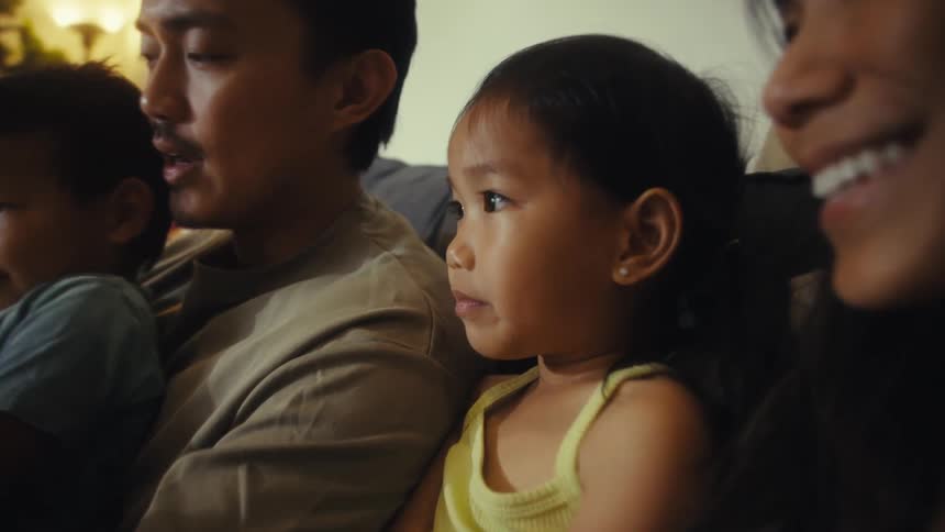 A father is reading a book to his family on the couch