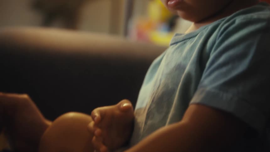 A person holding a toddler while reading a storybook
