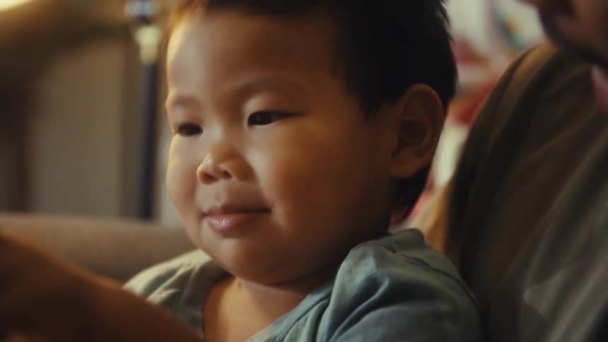 Family sitting together on a couch smiling and playing and the young boy gets suddenly scared indoors during day time