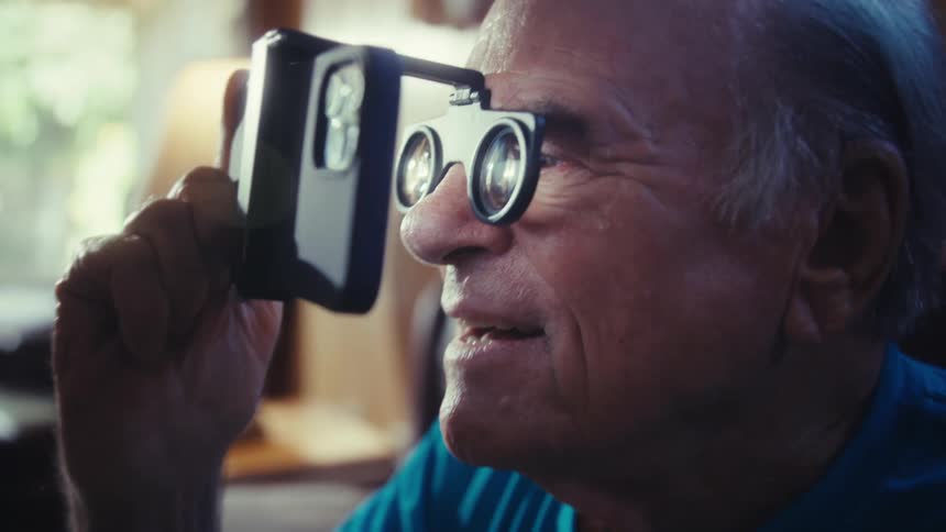 The man holds the phone close to his face while smiling