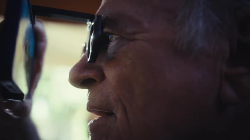 Elderly man with magnifying glasses interacting with a smartphone