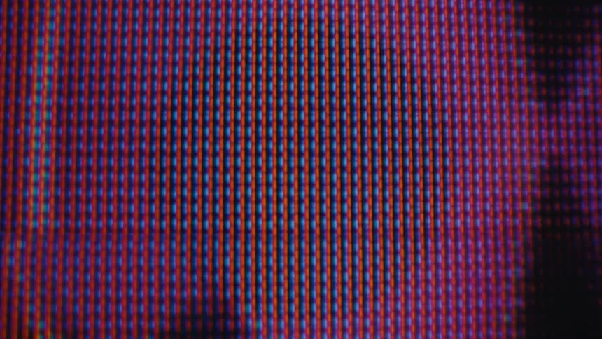 The video shows a closeup pixelated view of an audio frequency wave on a screen the wave which is a mix of magenta purple and blue colors is moving as if to the rhythm of sound