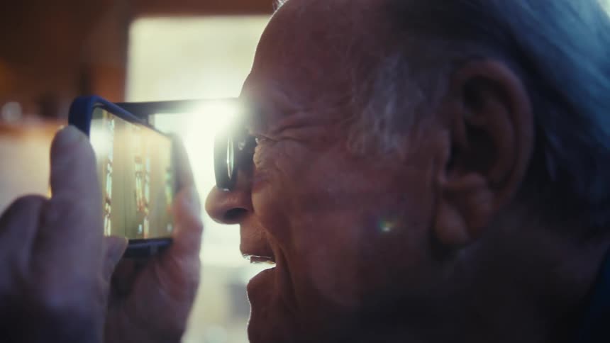 A man happily watches something on his phone