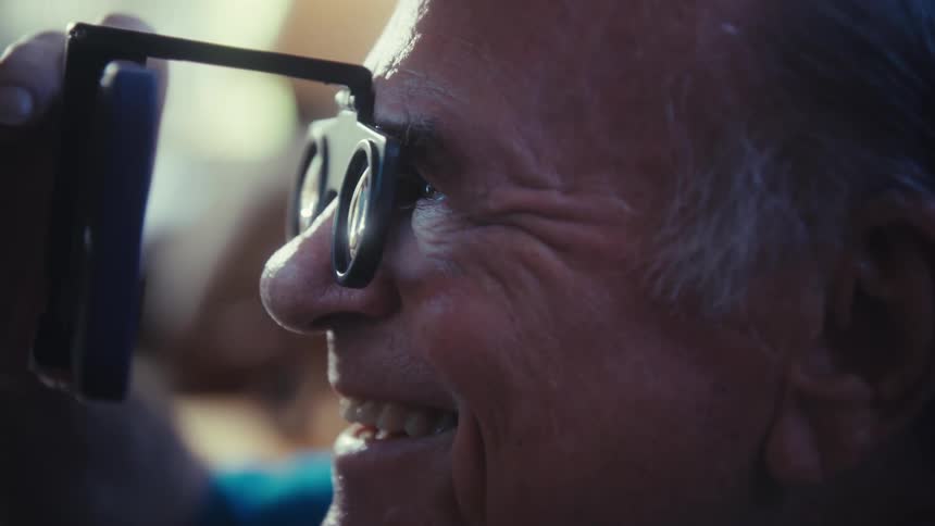 The man laughs while watching something on his cell phone