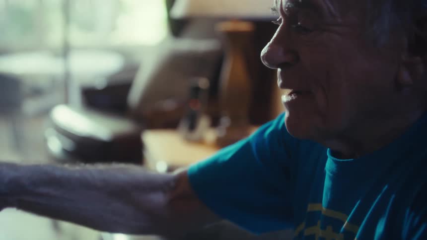 Elderly man sitting with his hands on his head celebrating