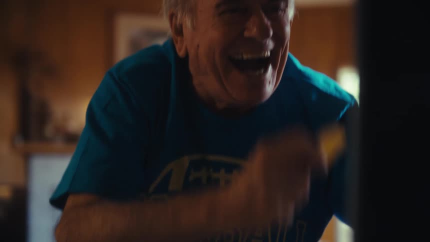 The man is cheering at a television screen